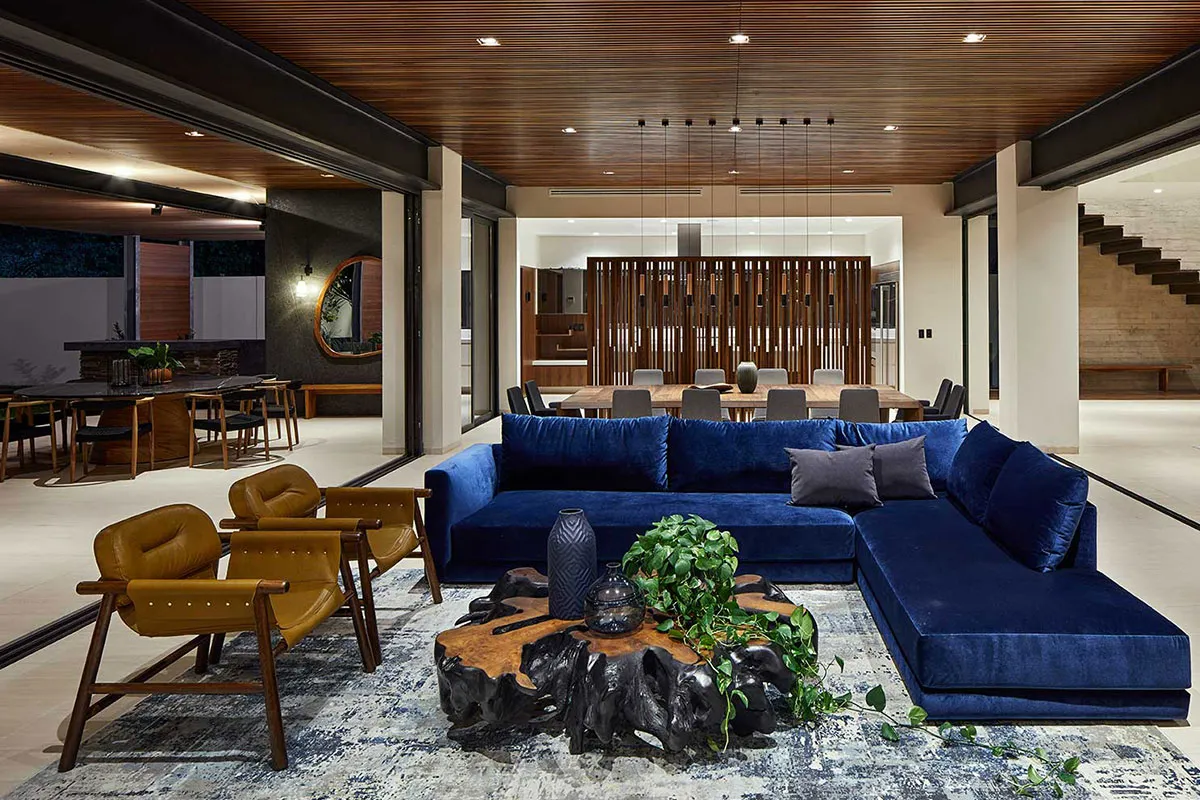 Contemporary living room with deep blue velvet sofa and wood-accented ceiling, blending color and texture.