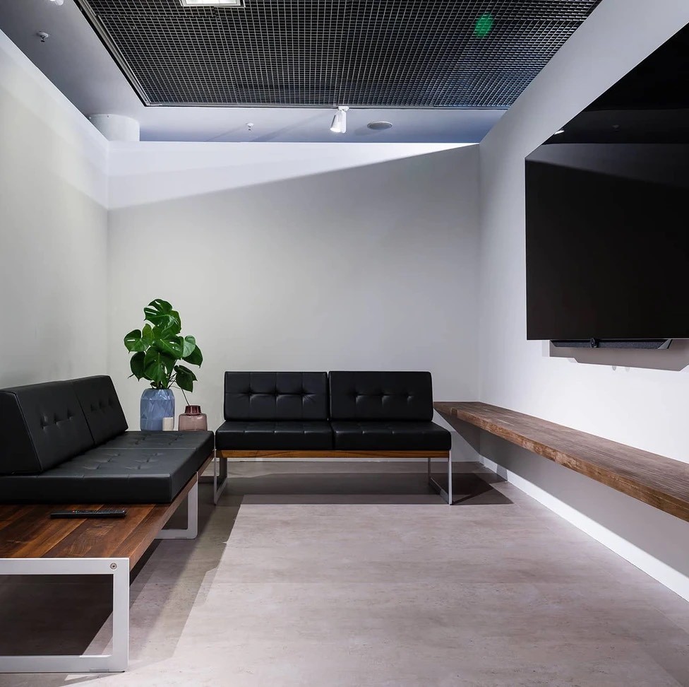 Tidy modern lounge with black seating, wooden bench, and green plant decor