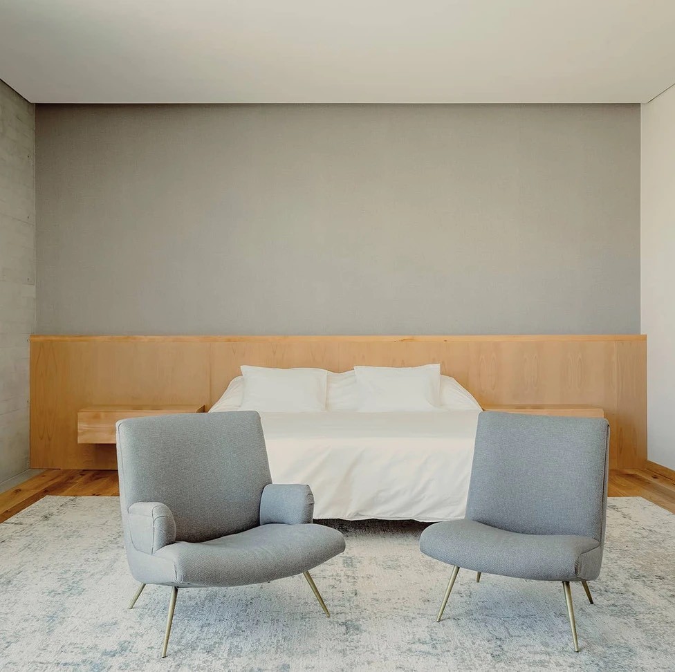 Clean and uncluttered bedroom with neutral tones and modern grey chairs